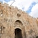 A historic stone gate with an arched entrance and fortified walls featuring decorative carvings